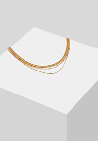 Collier superposé doré présentant plusieurs chaînes de textures et de longueurs variées, incluant des maillons plats et ronds. Fini lisse.