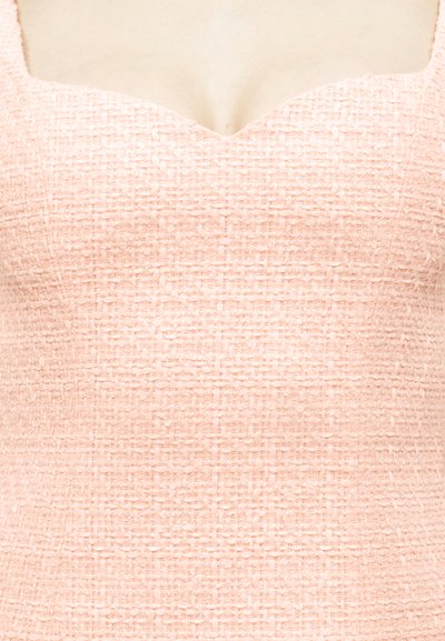 Prim-plan al unei rochii roz texturate fără mâneci, cu decolteu în formă de inimă, pe o tonă de piele deschisă.