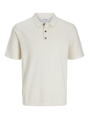 Polo shirt blanc à manches courtes en tissu doux et texturé, avec un col et trois boutons foncés sur le plastron.