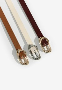 Tre læderbælter: brun, cremefarvet og mørkerød, med metalspænder med en poleret overflade og glat tekstur.