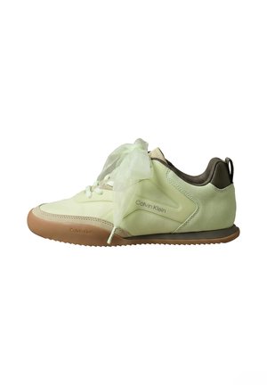 Jasnozielony sneaker Calvin Klein z przezroczystymi szerokimi wstążkowymi sznurówkami i beżową gumową podeszwą, pokazany z boku na białym tle.
