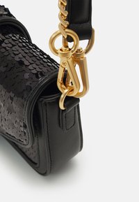 Zwarte leren handtas met een sequinkleurige textuur, gouden hardware en een kettingband bevestiging. Het ontwerp is compact en gestructureerd met ronde hoeken.