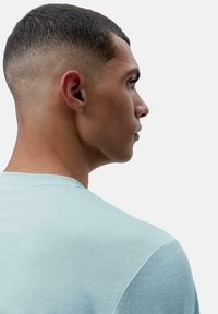 Svijetloplava majica s kratkim rukavima i okruglim izrezom, izrađena od mekanog materijala, s glatkom teksturom. Prikazana sa strane, ističe izrez.