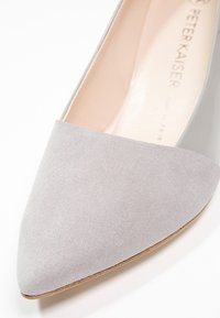 Chaussure plate à bout pointu avec tige en daim gris clair et semelle intérieure beige portant la mention "Peter Kaiser" sur un fond blanc.