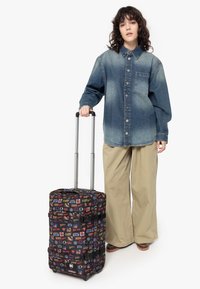 Wheeled suitcase with a black fabric exterior featuring colorful comic character graphics, a lockable zipper, and retractable metal handle.