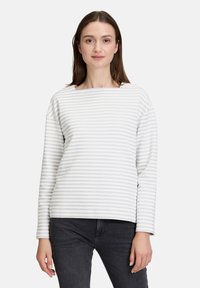 Haut à manches longues rayé en blanc et gris clair, avec un col bateau et une coupe décontractée. Texture douce avec un motif côtelé subtil.