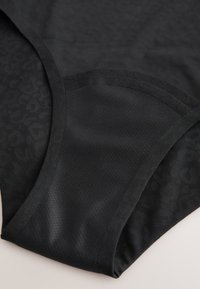 Parte inferior de bikini negra con tela de textura suave, con un panel que muestra un sutil estampado de leopardo en un lado.