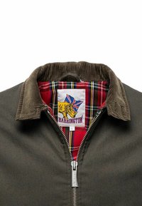 Veste Harrington avec un extérieur vert foncé, un col en velours côtelé et une doublure à carreaux rouges, ornée d'une étiquette logo audacieuse affichant un rhinocéros.