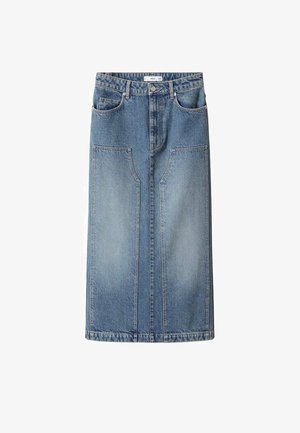 Femme portant un haut blanc à manches longues, une jupe maxi en jean taille haute bleu clair avec de grandes poches avant, et des sandales noires à brides.