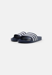 Marineblå slide-sandaler laget av syntetisk materiale med tre hvite horisontale striper på oversiden og strukturert fotseng for bedre grep.