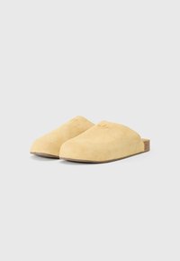 Yellow suede slip-on clogs with a rounded toe and a textured surface. They feature a low profile and a brown cork-like sole.