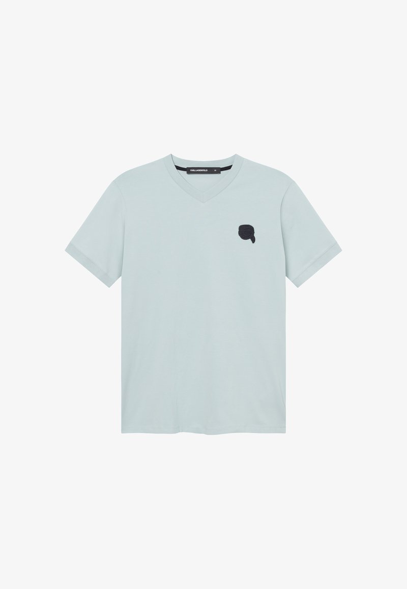 T-shirt bleu clair à col en V et manches courtes avec un petit logo noir sur le côté gauche de la poitrine représentant un visage stylisé avec une queue de cheval.