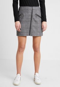 Grå och svart rutigt minikjol med två fickor med dragkedja och silverdetaljer, med rak skärning och en mjuk textur.