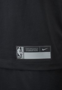 Camisola atlética preta com um tecido suave e uma textura em malha. Inclui um rótulo com o logo da NBA e a marca Nike com detalhes específicos de engenharia.