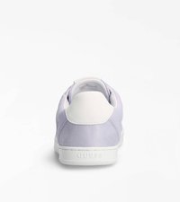 Sneaker viola e bianco con superfici lisce e testurizzate, forma arrotondata e tallone con marchio. Suola in gomma con battistrada sagomato.