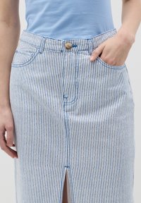 Gonna di jeans a righe blu e bianche con spacco frontale, dotata di chiusura a bottoni e tasche anteriori. Tessuto testurizzato con dettagli di cucitura.