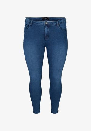 Jean skinny en denim bleu foncé, avec une taille haute, des poches avant et des zips au niveau des chevilles. Texture lisse avec un minimum de détails de couture.
