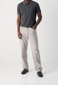 Tmavě šedé polo tričko, krátké rukávy, s límečkem; světle šedé rovné džíny; černé boty; decentní logo na tričku.