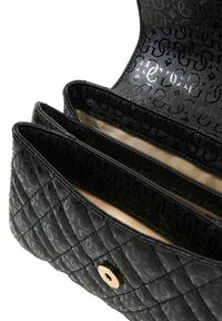 Sac à main en matière matelassée noire avec motif logo, comprenant trois compartiments et une fermeture à bouton pression doré. L'intérieur est beige.