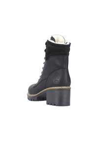 Black leather ankle boot with a textured suede collar, lace-up front, chunky heel, and a soft, white fur lining. Rounded toe design.