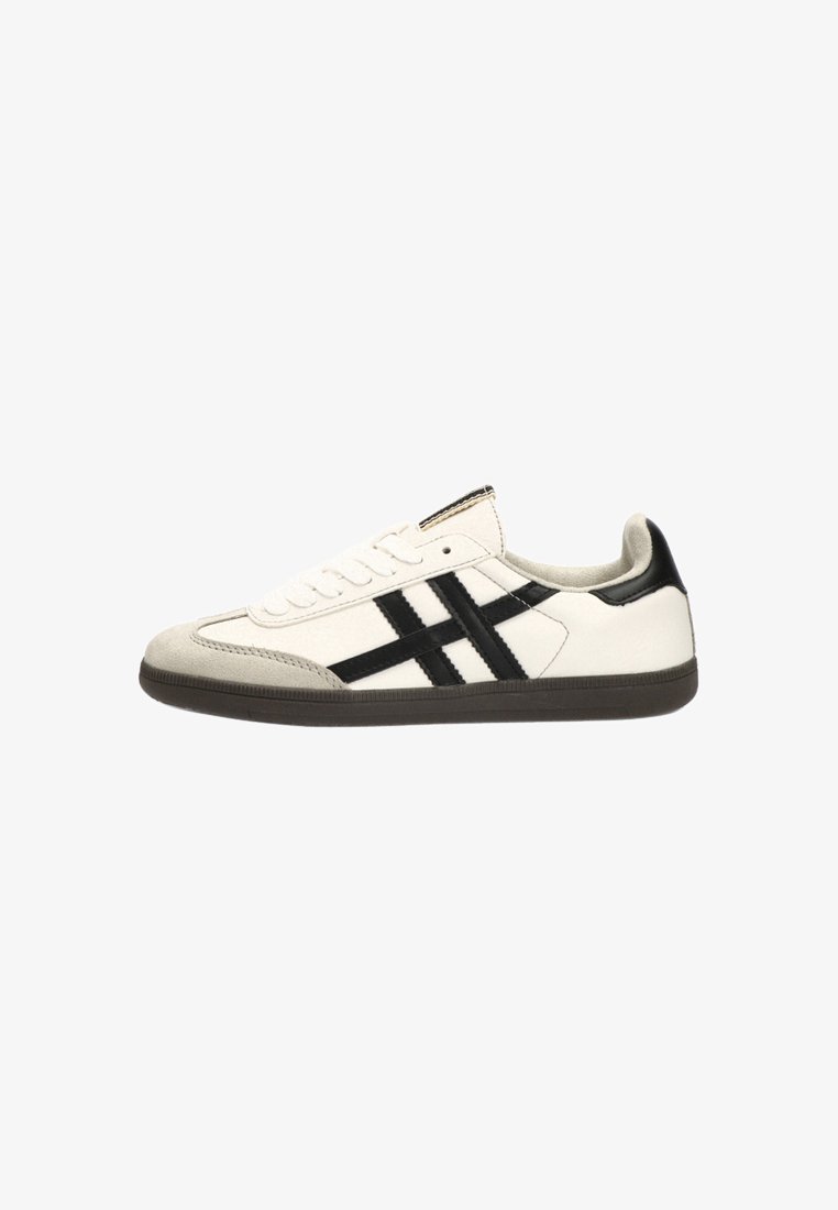 Zapatilla blanca con acentos negros, hecha de cuero y ante. Presenta tres franjas horizontales, punta redonda y suela de goma con agarre texturizado.