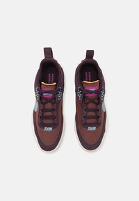 Nike tenisice s prozračnim smešastim gornjim delom u smešastoj boji, tirkiznim i ljubičastim detaljima, teksturiranim vezicama i svetlosivim potplatom.