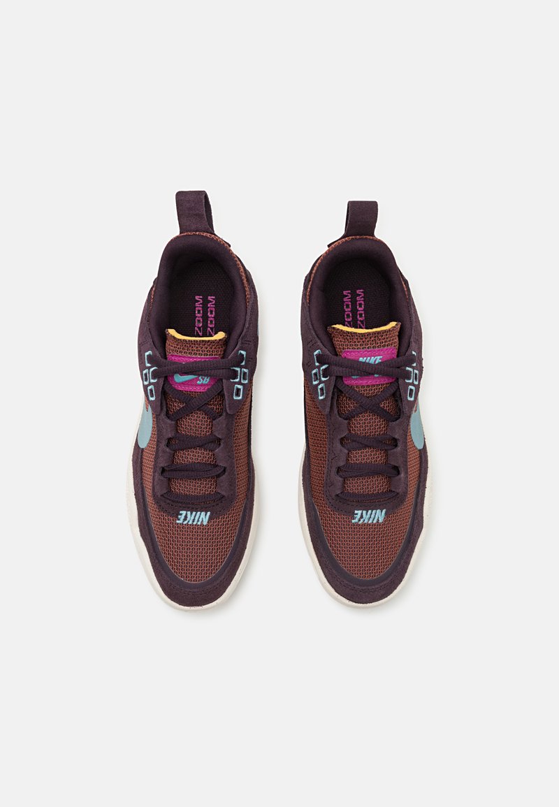 Baskets Nike avec une tige en maille respirante marron, des accents turquoise et violet, des lacets texturés et une semelle extérieure gris clair.