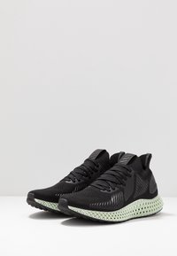 Zapatillas deportivas negras con parte superior texturizada y cordones, que cuentan con una exclusiva suela intermedia impresa en 4D de color verde claro y una suela exterior de goma negra.