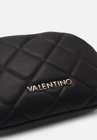 Svart kviltad läderkuvert med guld "Valentino"-logotyp. Har en slät yta, diamantskulpturer och eleganta rundade kanter.
