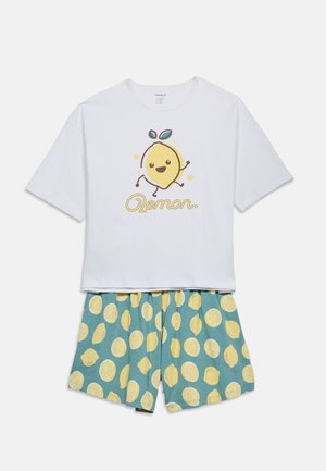 Witte top met korte mouwen met een grafiek van een lachende citroen en de tekst "Lemon", gecombineerd met blauwe shorts met gele citroenschijfjespatronen.