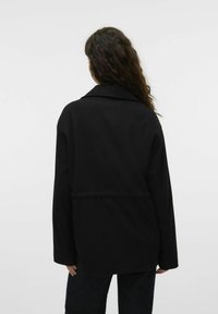 Must mustraga, millel on sälkede äär ja pikad varrukad. Omab lõdva lõiget ja sujuvat kanga tekstuuri. Ei ole nähtavaid mustreid ega aktsente.