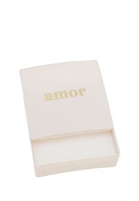 Scatola quadrata di colore crema con una finitura liscia; presenta la parola "amor" in rilievo in oro sul coperchio. L'interno è cavo e non foderato.