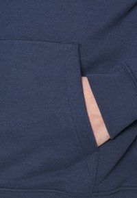 Mörkblå hoodie i texturerat tyg, med en framficka, ribbade ärmslut och en avslappnad passform.