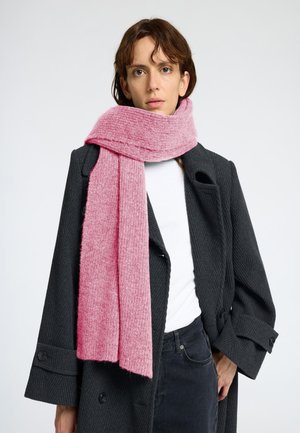 Zachte, geribbelde roze sjaal drapeert om de nek en complimenteert een donkere houndstooth jas. Heeft een lange, rechthoekige vorm en een warme textuur.