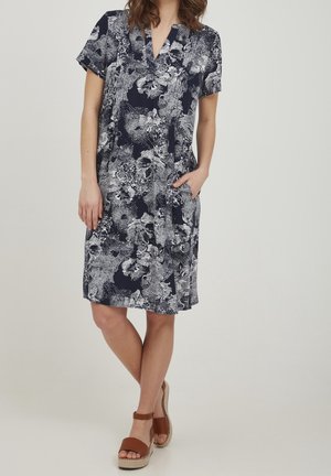 Marineblaues Floral-Kleid mit kurzen Ärmeln, V-Ausschnitt, seitlichen Taschen und leichtem, strukturiertem Stoff. Enthält weiße Blumenmuster im gesamten Kleid.