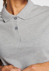Szara koszulka polo z teksturowaną tkaniną, z kołnierzykiem, dwoma ciemnymi guzikami oraz subtelnym przeszyciem przy listwie guzikowej.