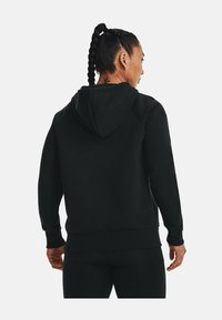 Haut à capuche noir avec une coupe décontractée, doté d'une capuche avec cordon de serrage, de poignets et d'ourlet côtelés. Texture lisse avec un design uni.