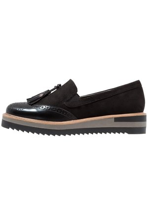 Zwarte loafer van suède en lakleer met tassel-detail, geperforeerde neus en gelaagde zool met beige en grijze strepen.