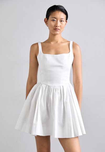 Robe blanche sans manches avec un décolleté carré, corsage ajusté et jupe évasée plissée, fabriquée en tissu léger avec une texture lisse.