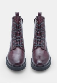 Stivaletti in pelle borgogna con lacci grigi, punta rotonda e cerniera laterale. Presentano una suola nera spessa e una texture liscia.