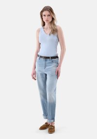 Hellblaues geripptes Tanktop, lässige Jeans in heller Waschung und braune Loafer mit Kettendetail. Glattes Material und bequeme Passform.