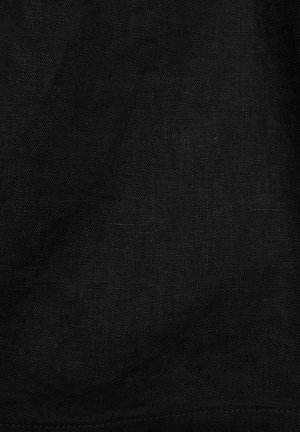 Zbliżenie tekstury czarnej lnianej tkaniny pokazujące drobne, tkanine włókna i subtelne naturalne zagniecenia.