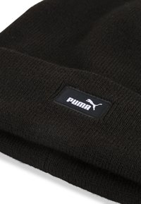 Cuffia nera lavorata a maglia con risvolto, caratterizzata da un'etichetta nera rettangolare che mostra il logo bianco "PUMA" e il profilo del logo. Texture morbida.