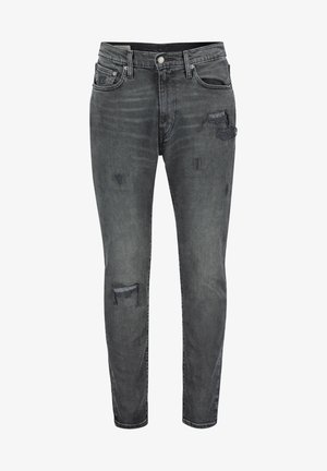 Jean slim gris foncé avec des patchs usés sur la cuisse et le genou, poches avant, passants pour ceinture et fermeture par bouton.