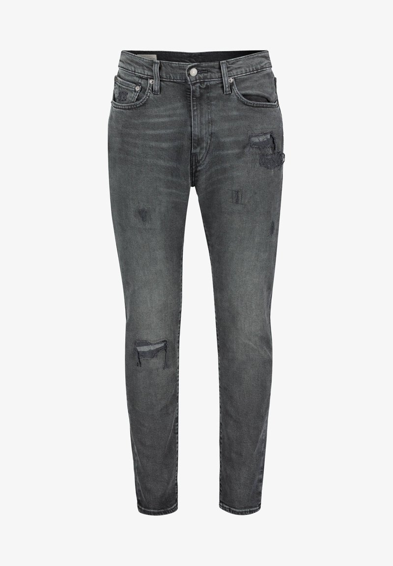 Jean slim gris foncé avec des patchs usés sur la cuisse et le genou, poches avant, passants pour ceinture et fermeture par bouton.
