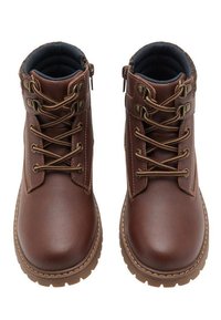 Un par de botas de tobillo de cuero marrón con cuellos acolchados, ojales de metal, punteras redondas y suelas de goma resistentes, vistas desde arriba.