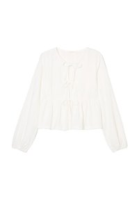 Blouse en coton blanc avec de longues manches légèrement bouffantes, encolure ronde et détail de nœud à l'avant. Tissu texturé avec un motif à œillets réparti uniformément.