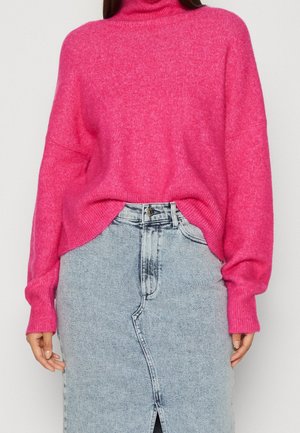 Helle rosa, übergroße Rollkragenpullover aus weichem Material, kombiniert mit einem hellblauen Jeansrock mit einem Schlitz vorne und verblassten Details.