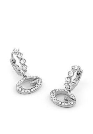 Boucles d'oreilles créoles en argent avec des pierres précieuses transparentes et des pendentifs ovales suspendus incrustés de petites pierres transparentes sur fond blanc.