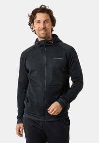Zwarte zip-up hoodie met een gestructureerde afwerking, voorzien van een capuchon, twee zakken en een logo op de borst. Geribde manchetten en zoom.